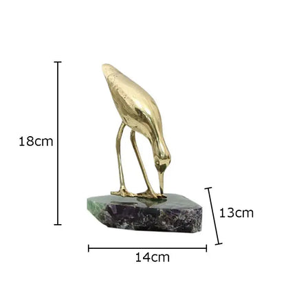 Golden brass bird desk ornament with slender legs and curved beak on polished green and purple marble base
