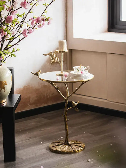 Golden brass bird tree side table with reflective glass top and intricate branch-like base for living room decorbites brass bird decor
