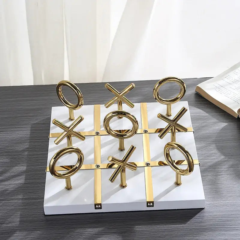 Golden chessboard metal handicraft tic-tac-toe set with gold metallic pieces on white marble base for decorbites decor