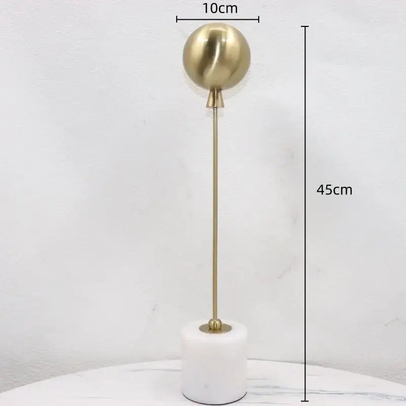 Golden geometric balloon metal ball sculpture with a 10cm gold-toned sphere on white marble base for living room decor