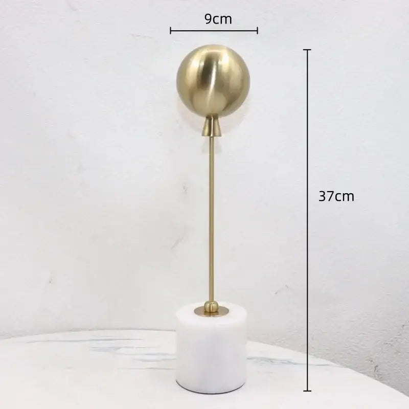 A sleek 37cm tall golden geometric balloon metal sphere lamp with polished brass finish on white marble base decorbites decor