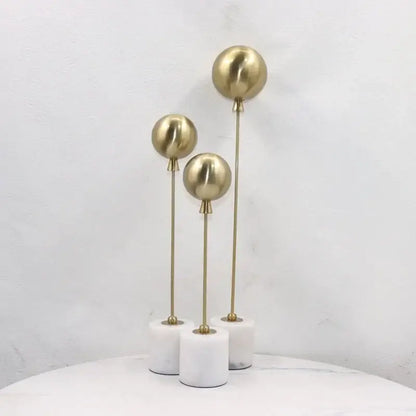 Set of three golden geometric balloon metal ball sculptures on white marble bases for living room decorbites decor