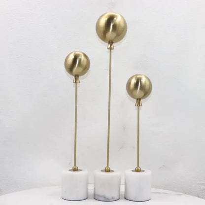 Set of three golden geometric balloon metal ball sculptures on white marble bases for living room decorbites decor