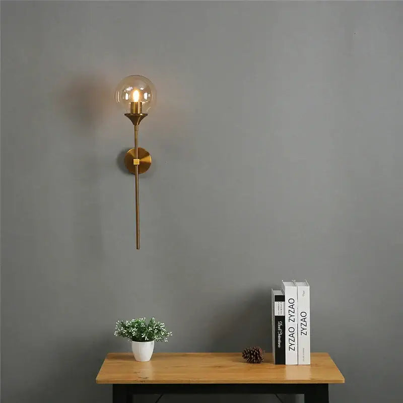 Gold-toned brass wall sconce with clear glass ball led globe and exposed filament bulb for bedroom decorbites golden glass