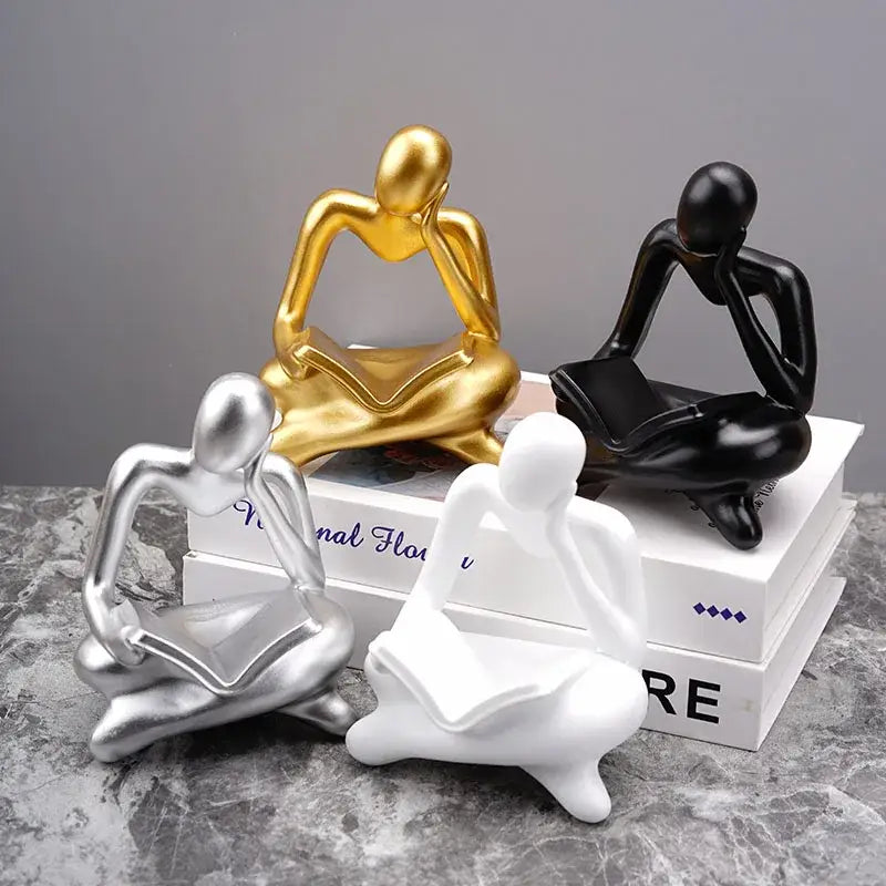 Set of four glossy resin figurines in gold black silver and white depicting the decorbites abstract thinker design