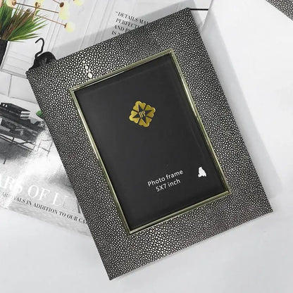 Black shagreen-textured photo frame with gold-toned inner border and flower emblem for decorbites gradient shell ceramic decor