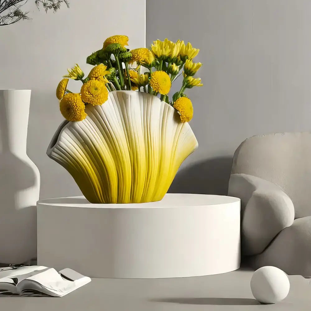 A vibrant yellow and white gradient shell ceramic vase filled with bright yellow flowers for living room decorbites decor