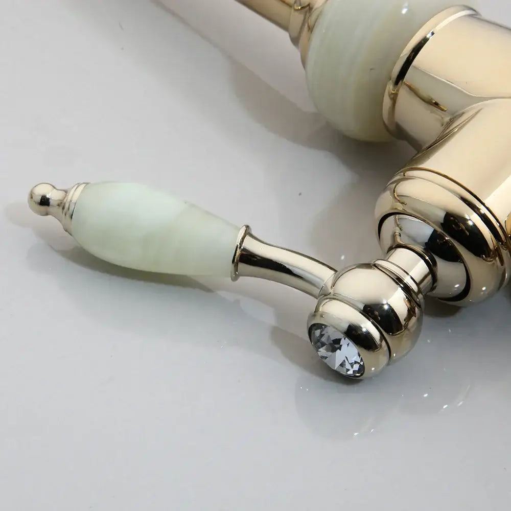 Elegant kitchen faucet handles with polished gold-tone metal, pale green jade ceramic, and faceted diamond base accents