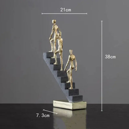 Golden man abstract resin sculpture featuring three golden figures ascending dark gray steps on a silver base decorbites golden man