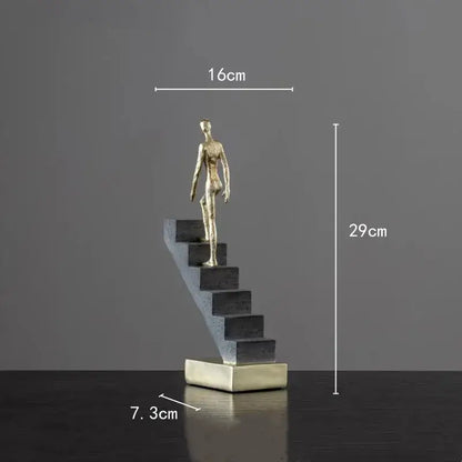 A sleek gold-toned man abstract resin figurine standing on a modern black and silver staircase decorbites golden man sculpture