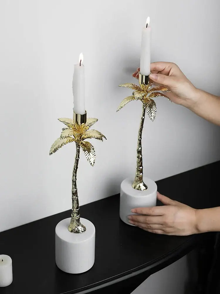 Golden metal candlestick palm tree candle holders with white candles on cylindrical marble bases for home decorbites decor