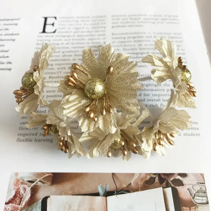Elegant gold-toned floral headband with textured fabric petals and metallic beads for decorbites green plant berry stamen decor