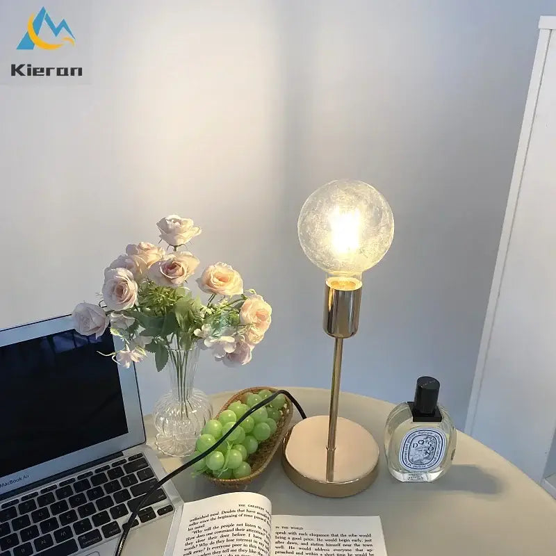 A golden modern led bedside lamp with a textured frosted glass globe bulb and slender gold-toned stem on a beige base