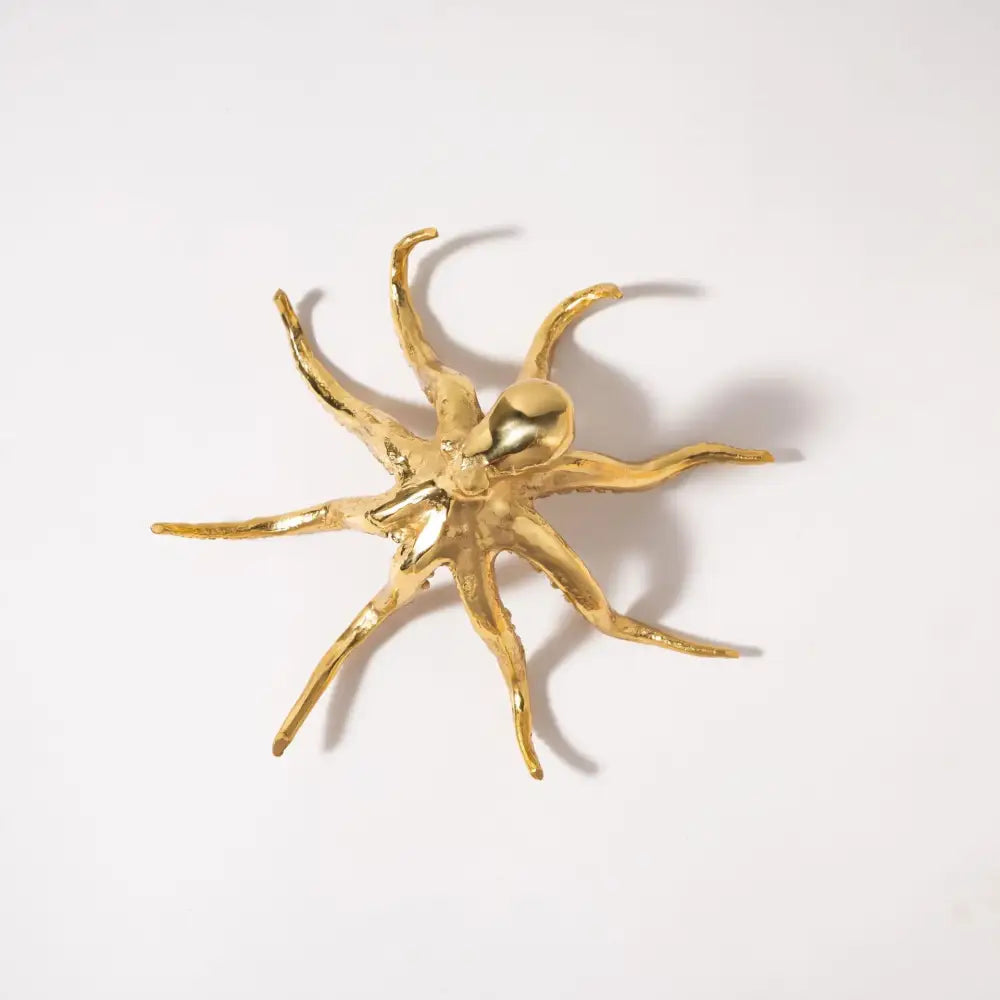 Golden octopus metal sculpture with articulated arms and polished reflective surface for living room decor by decorbites