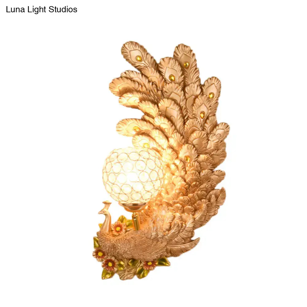 Golden peacock wall light with crystal shade featuring intricate feather details and a yellow green textured glowing globe bulb
