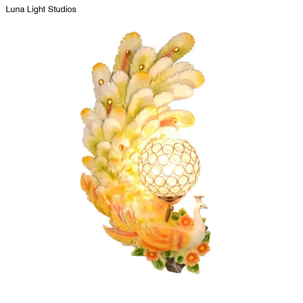 Golden peacock wall light with crystal shade featuring yellow green feathers and floral accents for living room decor