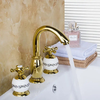 Golden plated bathroom faucet set with white ceramic handles featuring black floral detailing by decorbites