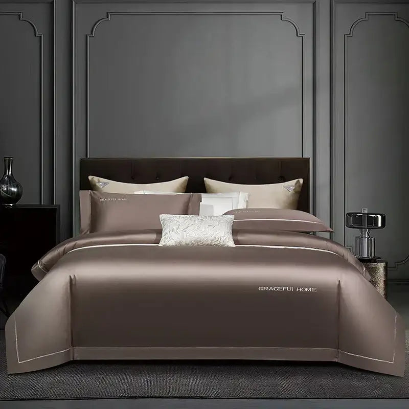 The golden satin egyptian cotton bedding set features a taupe satin duvet cover with white embroidery and gold logo