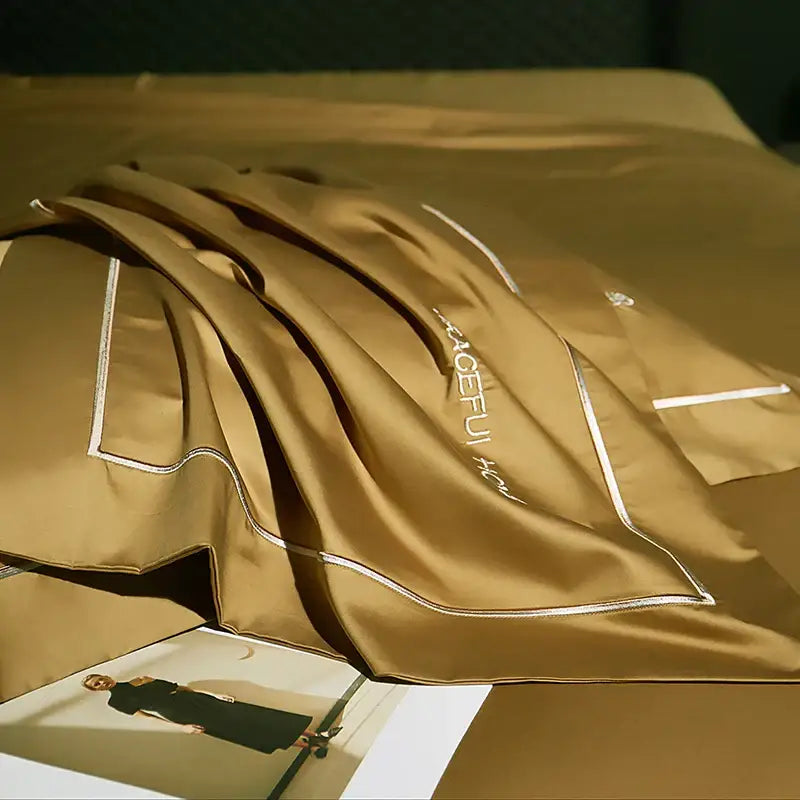 A luxurious gold satin pillowcase with white embroidered trim and aceful brand in decorbites 1000tc egyptian cotton bedding set