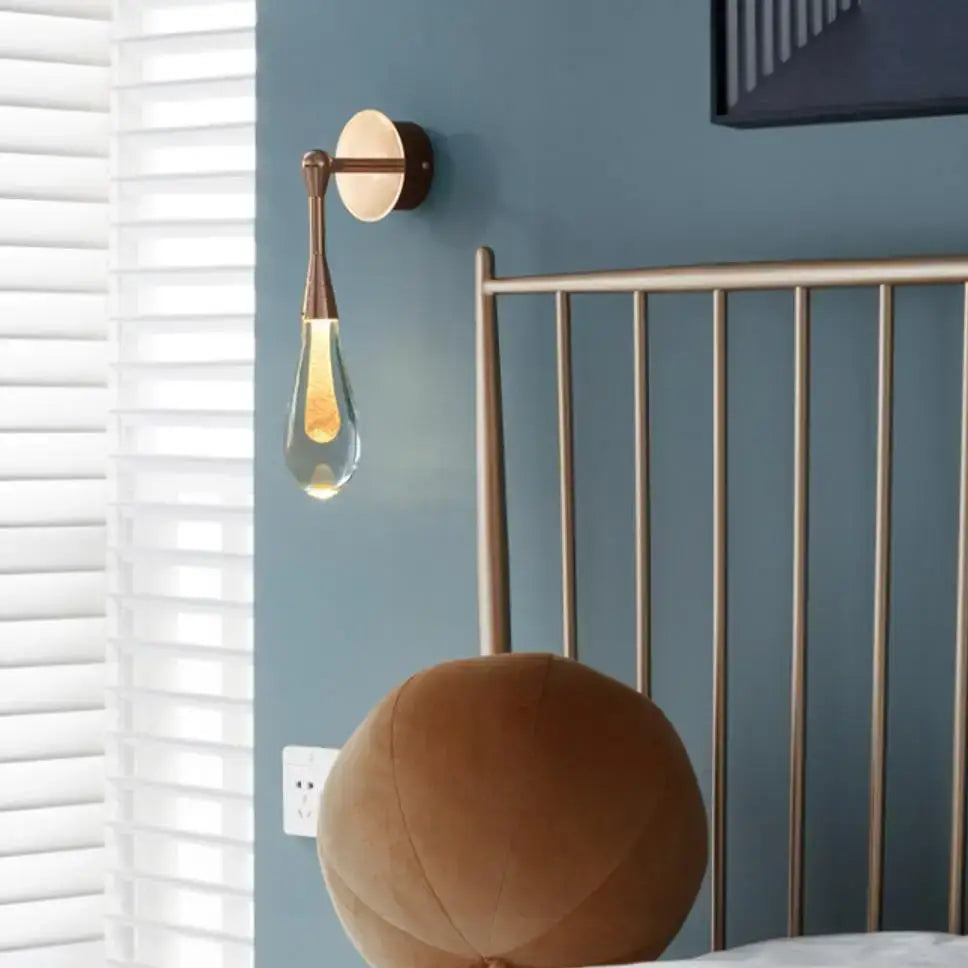 Brass-finished wall lights with clear teardrop glass bulbs emitting warm light for bedroom decorbites golden water droplets