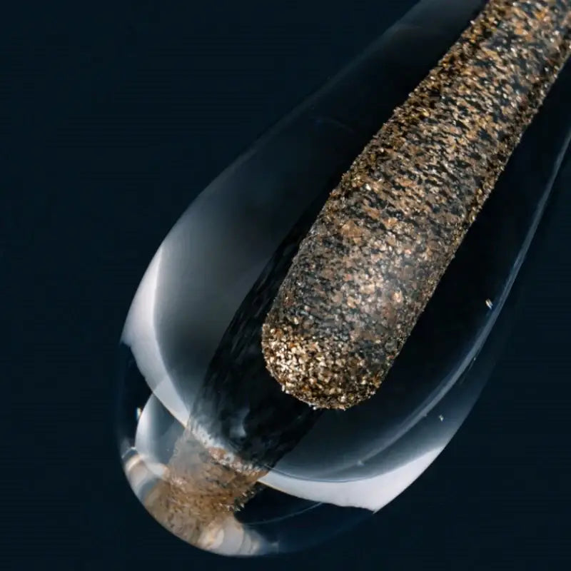 A decorbites golden water wall light featuring a textured dark brown and gold speckled cylinder inside a glass droplet