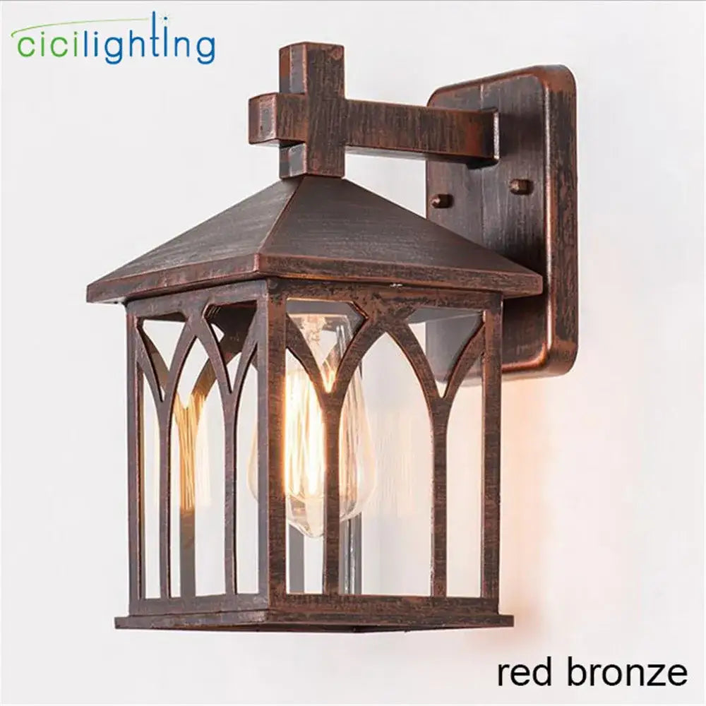 Red bronze gothic led wall lamp with arched glass panels and cross topped roof for garden courtyard use