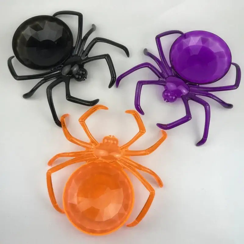 Three plastic skull spiders with faceted black purple and orange gemstone abdomens on gothic skull spider tray storage plate