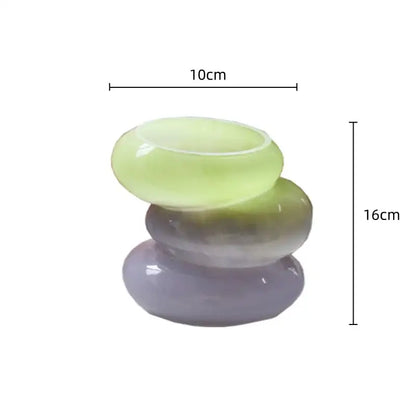 Stacked translucent jade-like stones in soft green and purple hues form a smooth centerpiece in a decorbites geometric glass vase