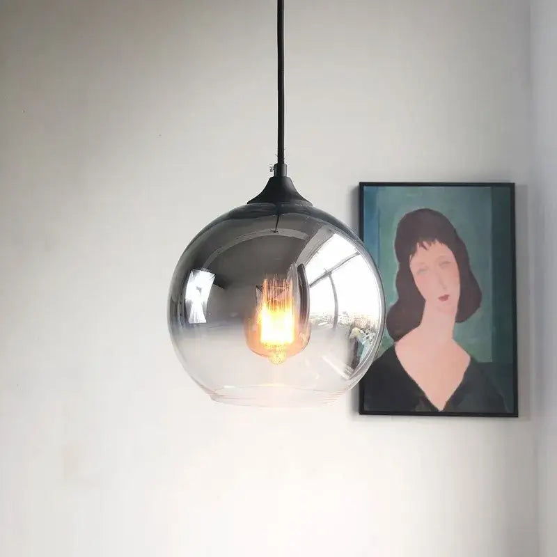 A sleek gradient glass ball chandelier set with black metal fixture and exposed filament bulb for dining room use
