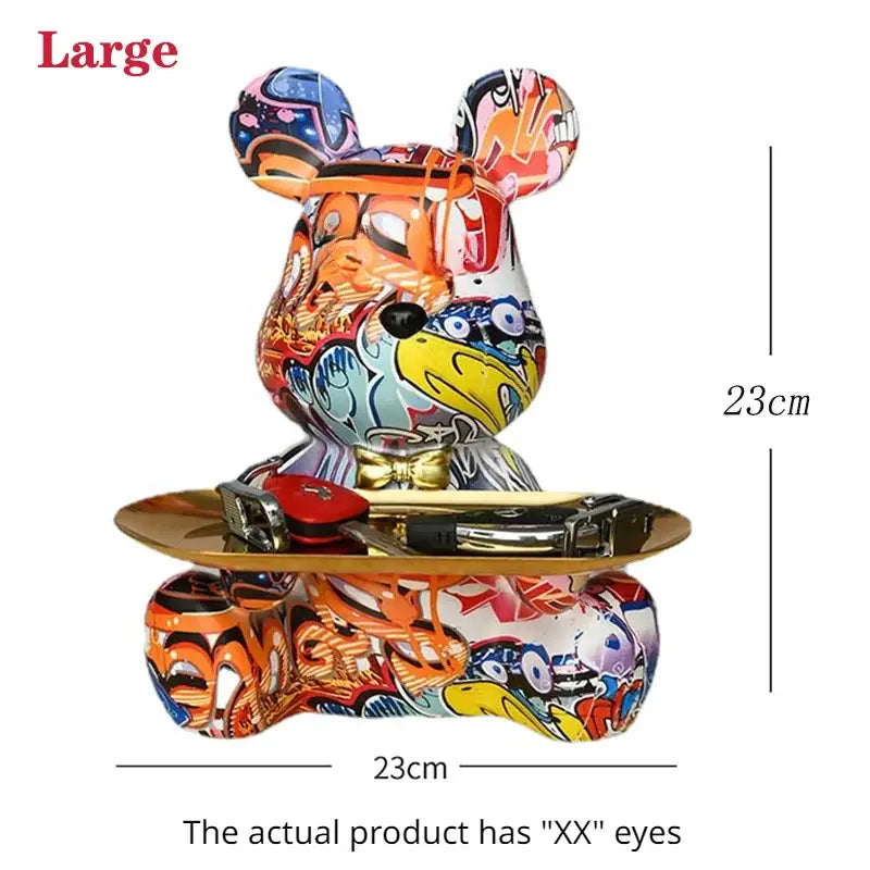 A large colorful gloss finish decorbites graffiti bear figurine with cartoonish eyes on a gold tray for living room storage