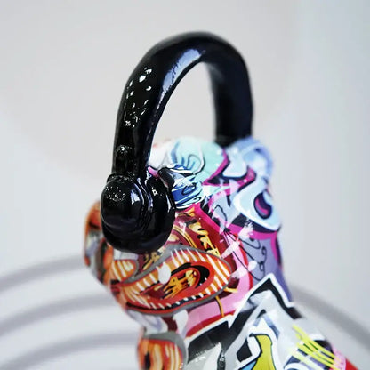 A glossy black resin handle with a curved finish atop a vibrant graffiti painted bulldog headphone figurine