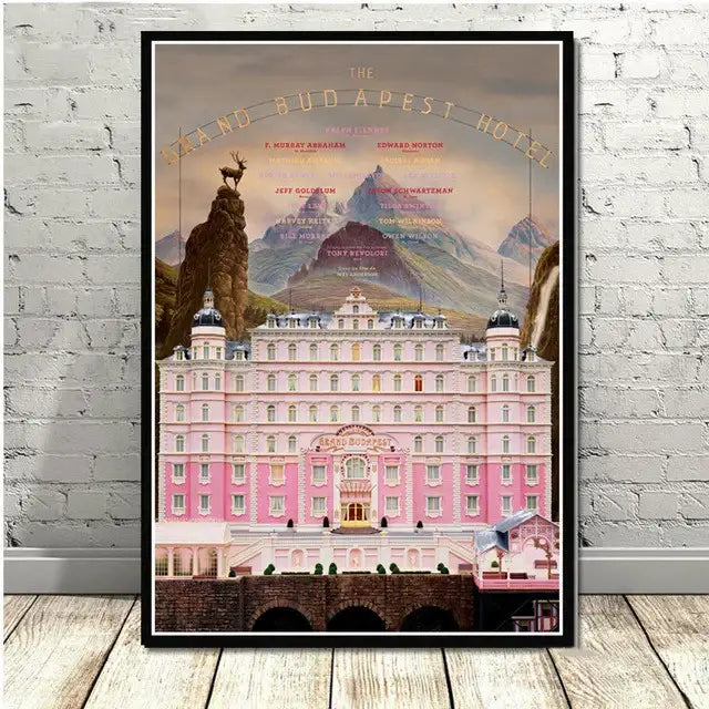A framed decorbites grand budapest hotel minimalist wall art featuring the pink ornate facade with mountainous scenery