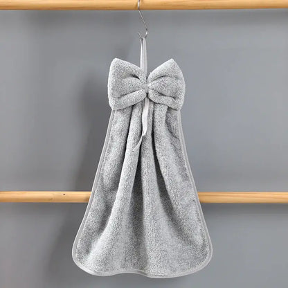 Gray terry cloth hand towels with a plush bowknot coral velvet design hanging on a hook by decorbites