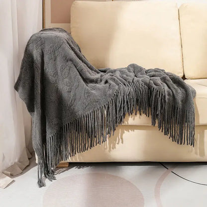A cozy gray cable knit blanket with fringe draped over a cream sofa perfect for knit blanket sofa decorbites decor