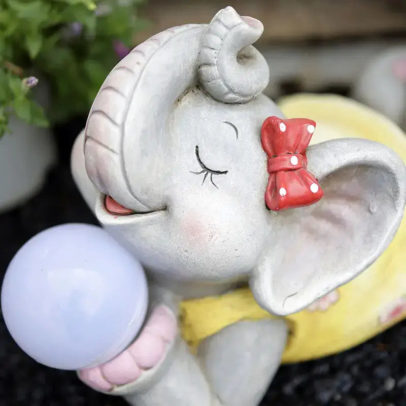 Gray ceramic elephant garden decoration figurine with closed eyes and red bow holding light blue sphere outdoor use
