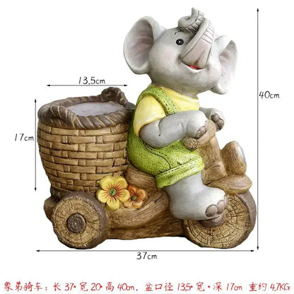 Gray ceramic elephant garden decoration wearing green vest riding wooden cart with woven basket details outdoors