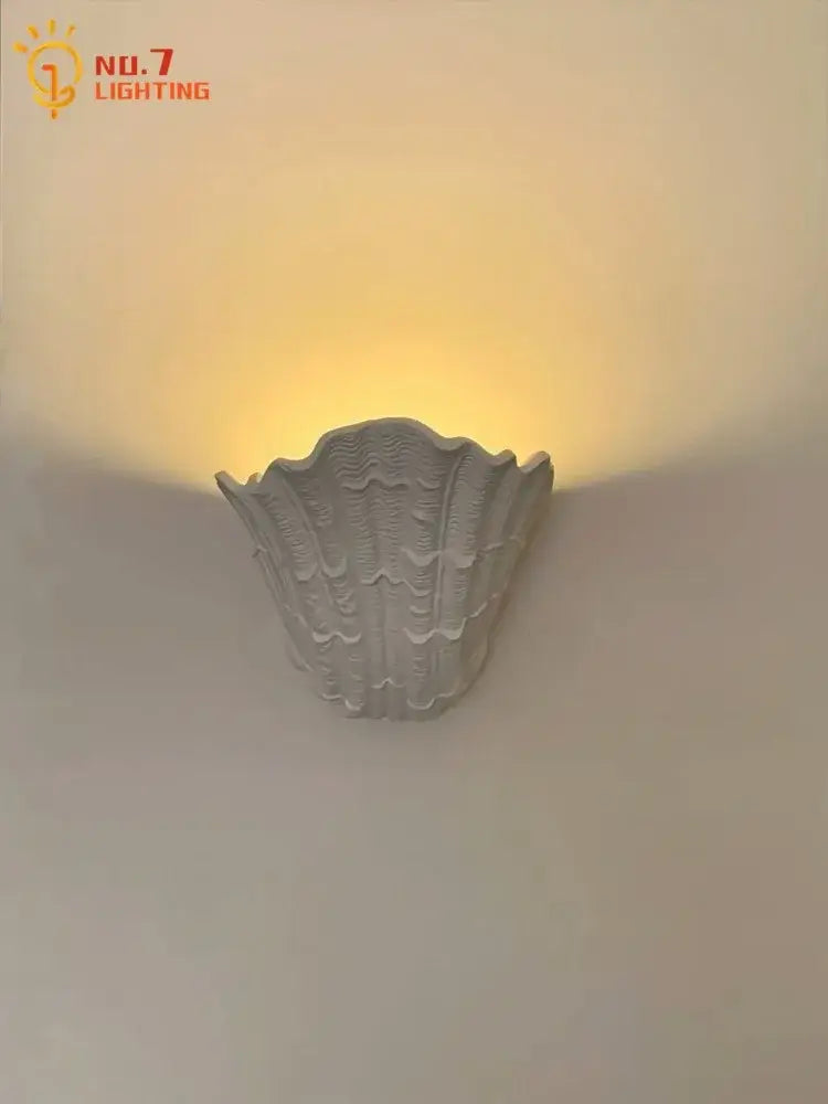 Gray gypsum shell led wall lamp with textured ridged surface designed as a shell-shaped bedroom sconce