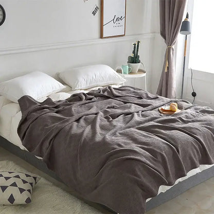 Gray herringbone cotton waffle towel quilt draped over bed with soft textured pattern for bedroom or office decorbites cotton waffle