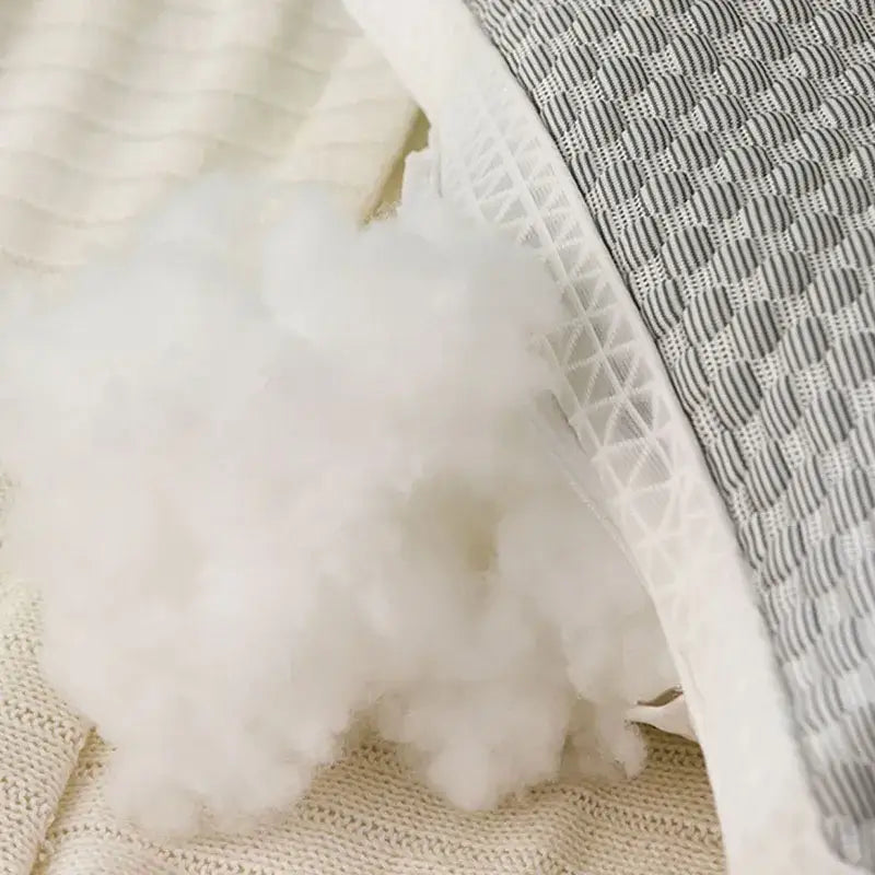White fluffy polyester stuffing spilling from a quilted gray ice rayon cooling pillow with geometric stitching for neck support
