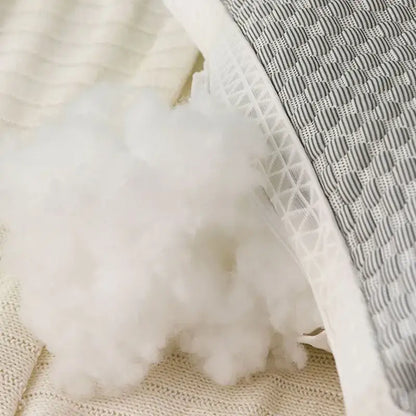 White fluffy polyester stuffing spilling from a quilted gray ice rayon cooling pillow with geometric stitching for neck support