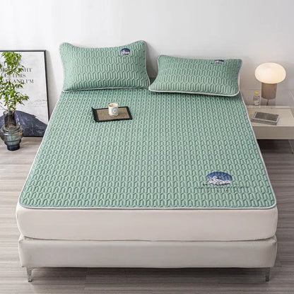 Mint green quilted latex bed mat with subtle mountain embroidery and white piping edges in a bed mat set