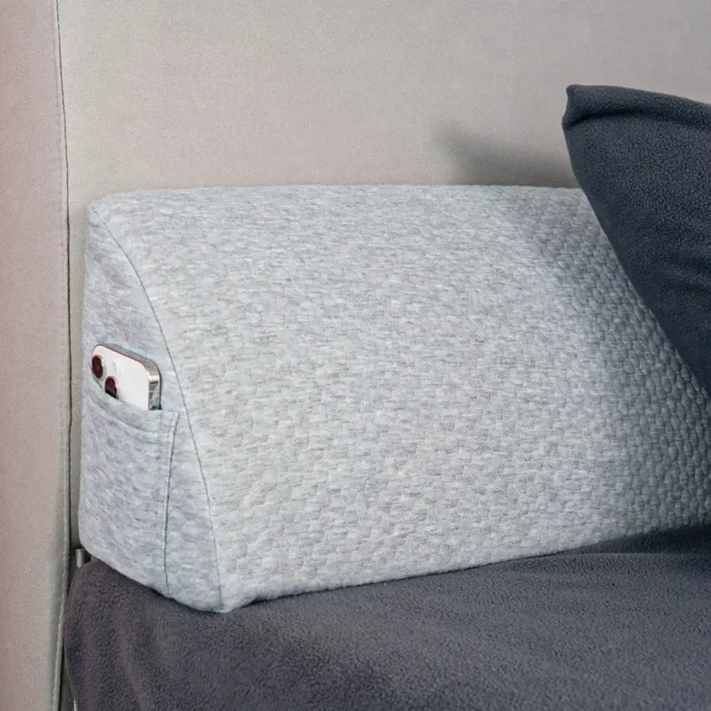 Gray textured memory foam bed wedge pillow with built-in pocket holding smartphone for bedroom mattress gap filler