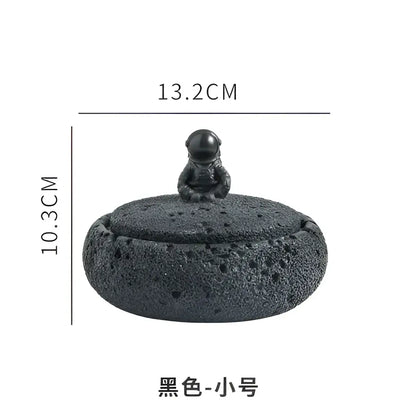 Black textured ceramic cement astronaut ashtray with a miniature astronaut figurine on its domed lid for living room use