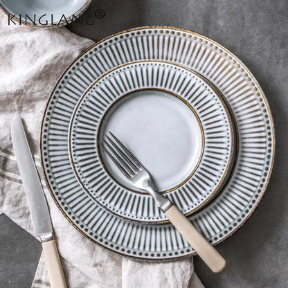 Set of three stacked matte white ceramic plates with gold-toned rims from the gray and white striped ceramic wedding tableware set