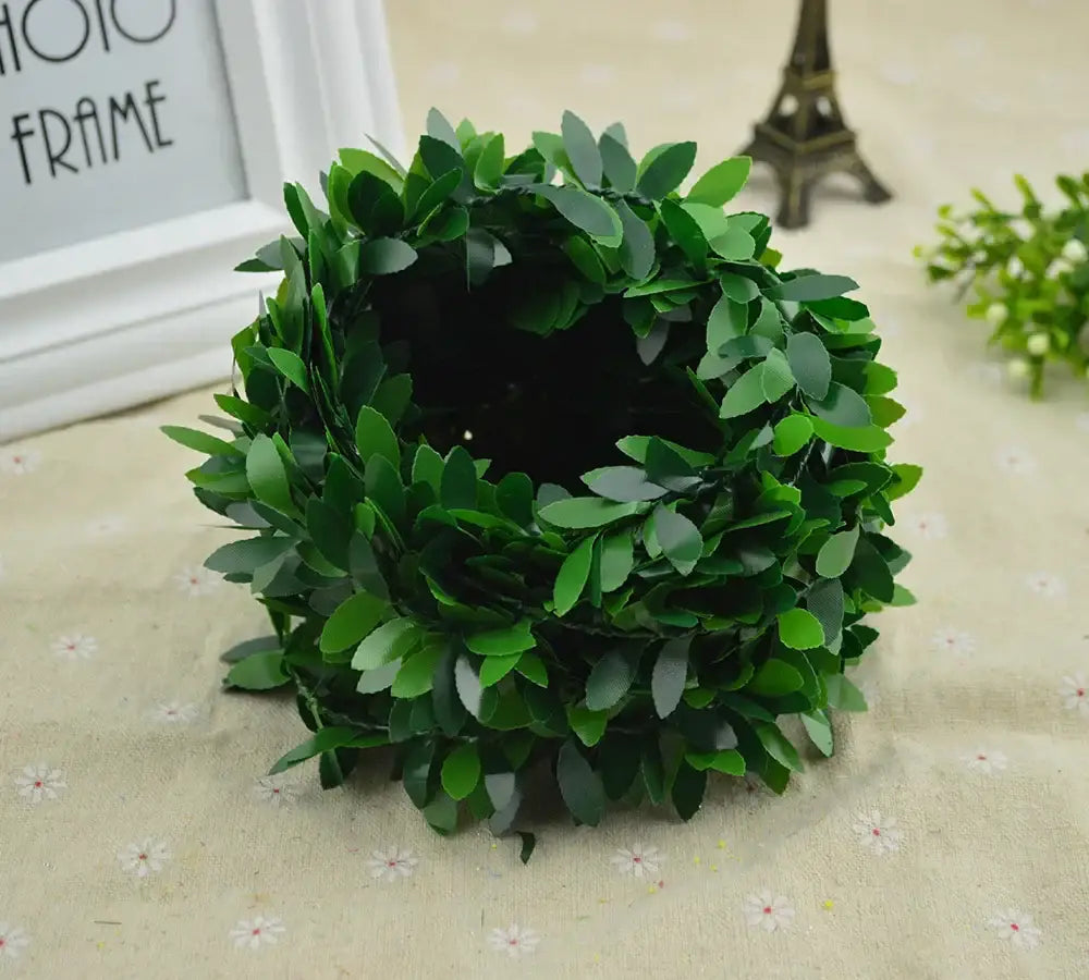 A lush, circular green leaf vine wreath garland made of artificial leaves with a dense, natural-looking texture for decor