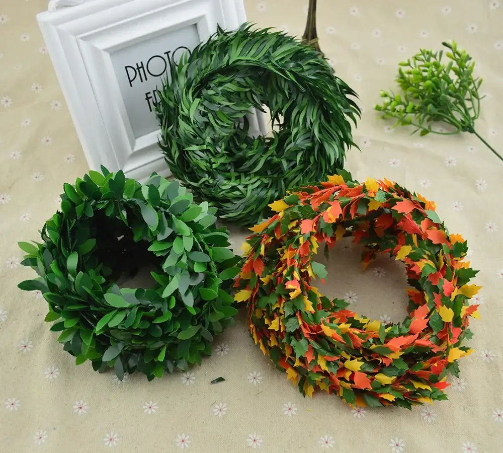 Three artificial leaf vine wreaths in green and autumn hues made of synthetic material for living room decor