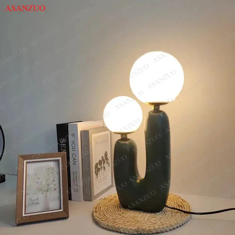 Modern green ceramic table lamp with double frosted glass spherical shades and a sculpted base for bedroom use
