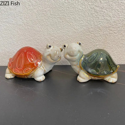 Two ceramic turtle statues with glossy orange and greenish blue shells as desk decoration trinket dishes