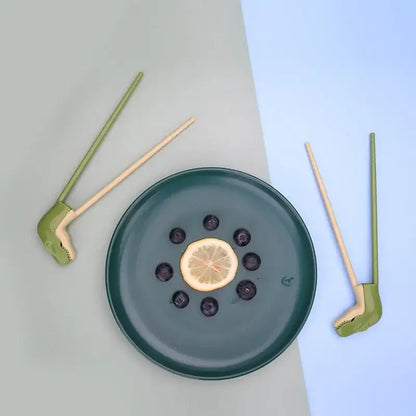 Dark green ceramic plate with sliced lemon blueberries shown with green dino chopsticks kids training set decorbites