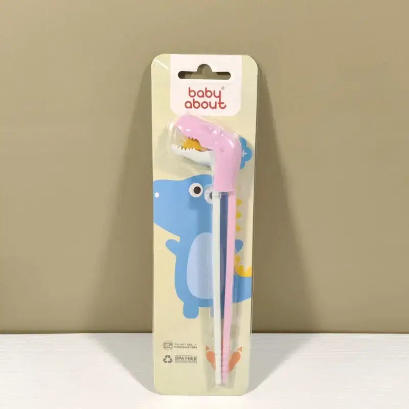 Pink dinosaur-shaped baby feeding utensils in baby about package for kids training with decorbites dino chopsticks